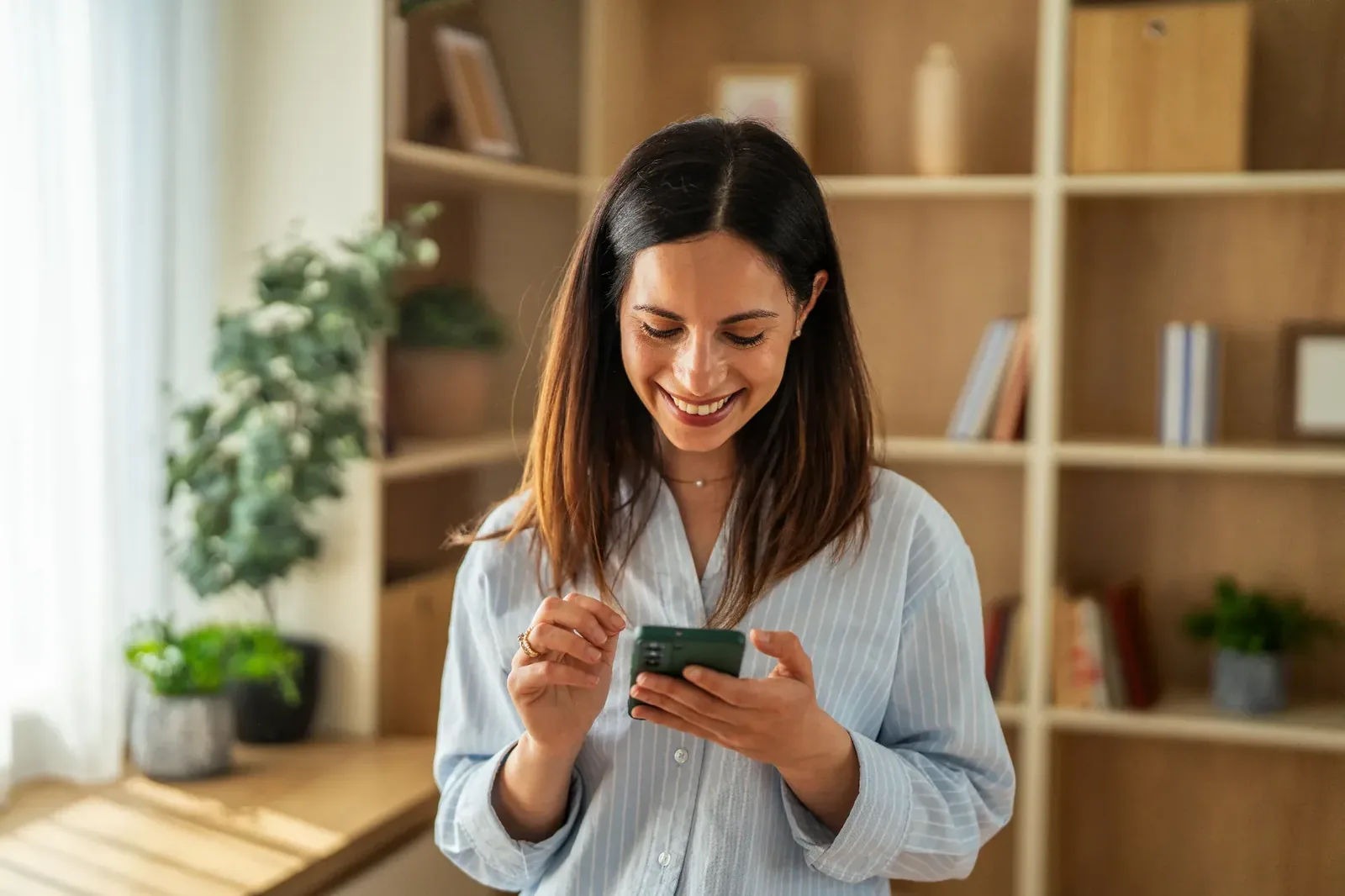 Mujer sonriendo mientras usa su celular