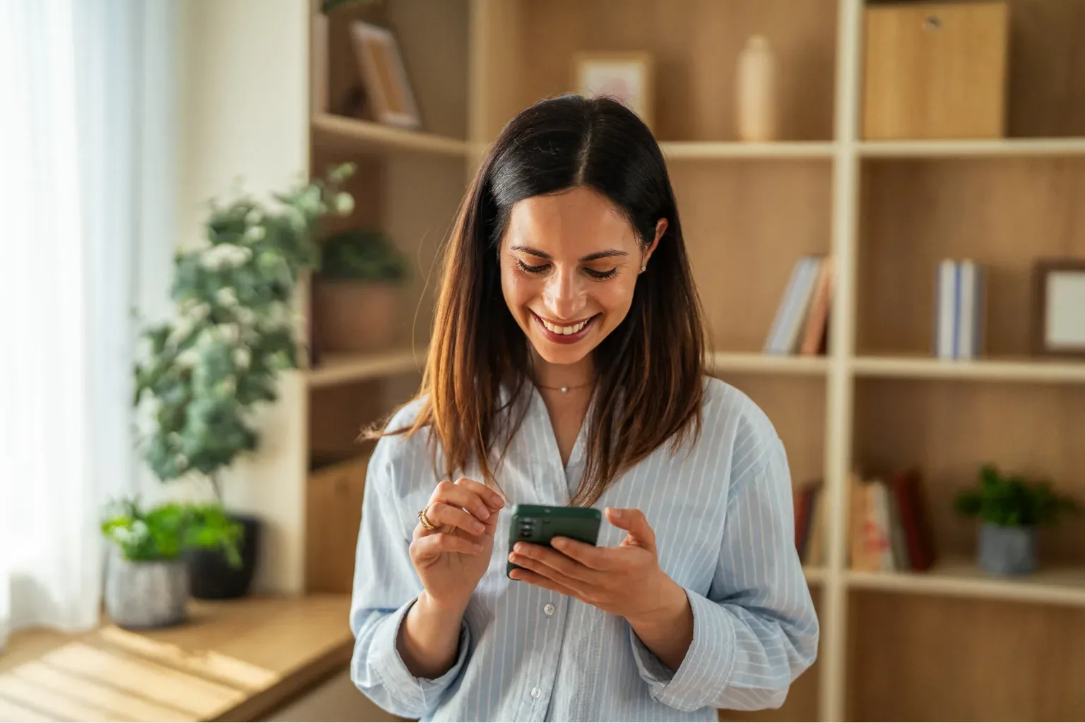 Mujer sonriendo mientras revisa su celular